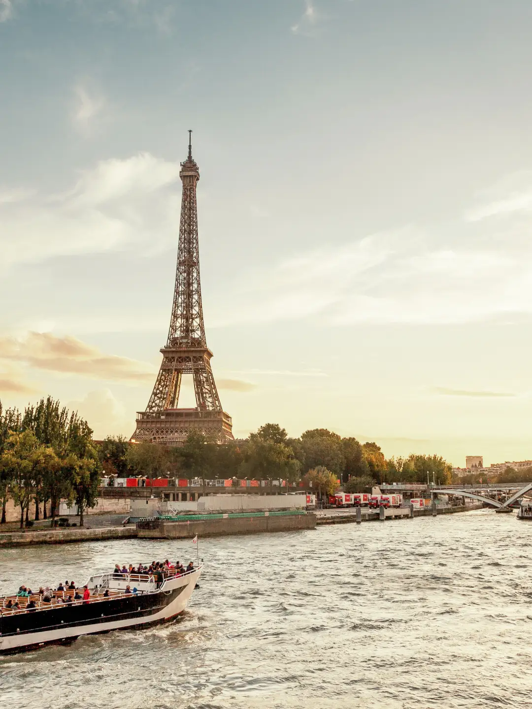 A tourist boat on the Seine with a view of the Eiffel Tower in Paris at sunset.