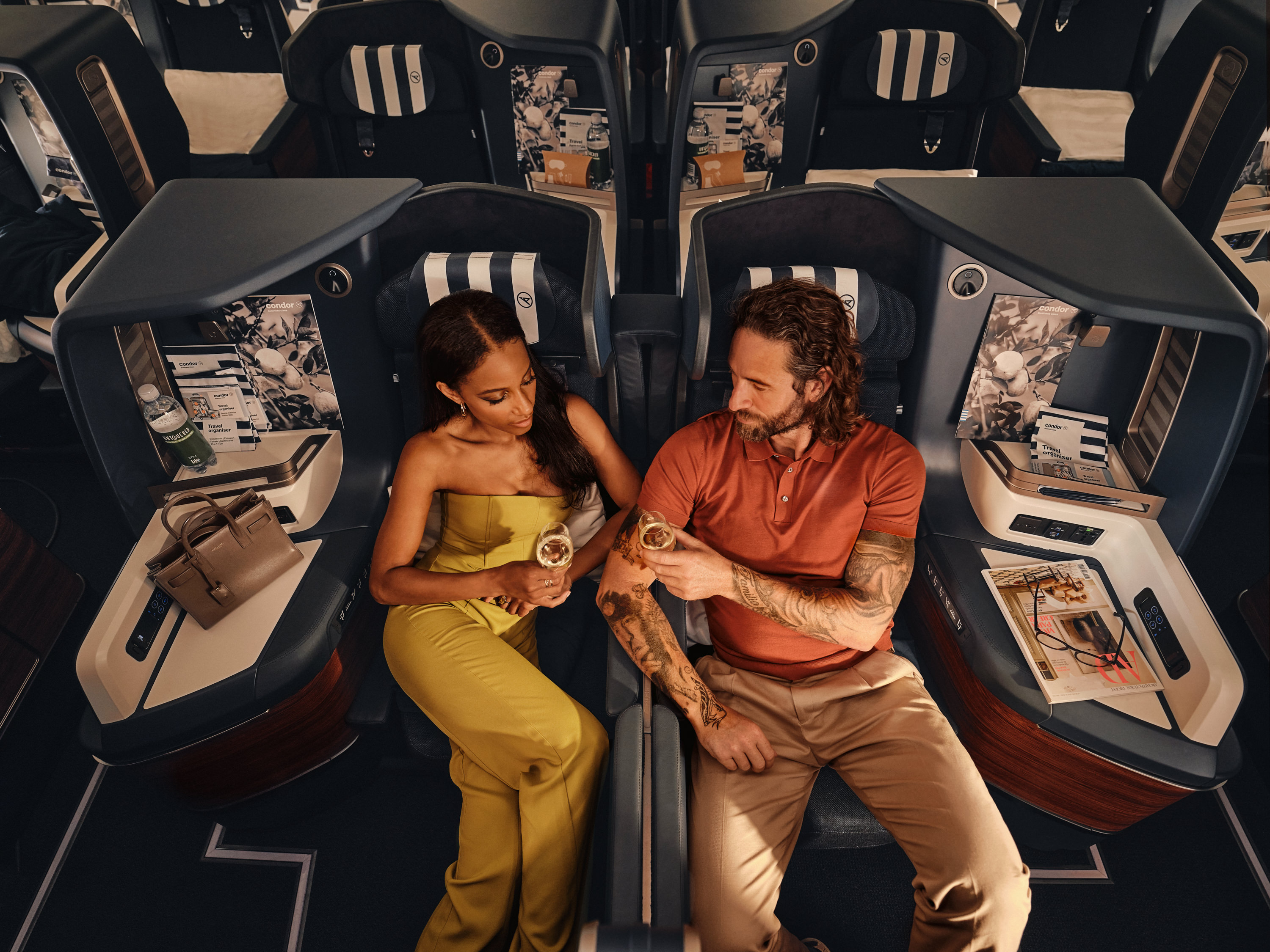 Two passengers enjoying business class aboard a Condor aircraft.