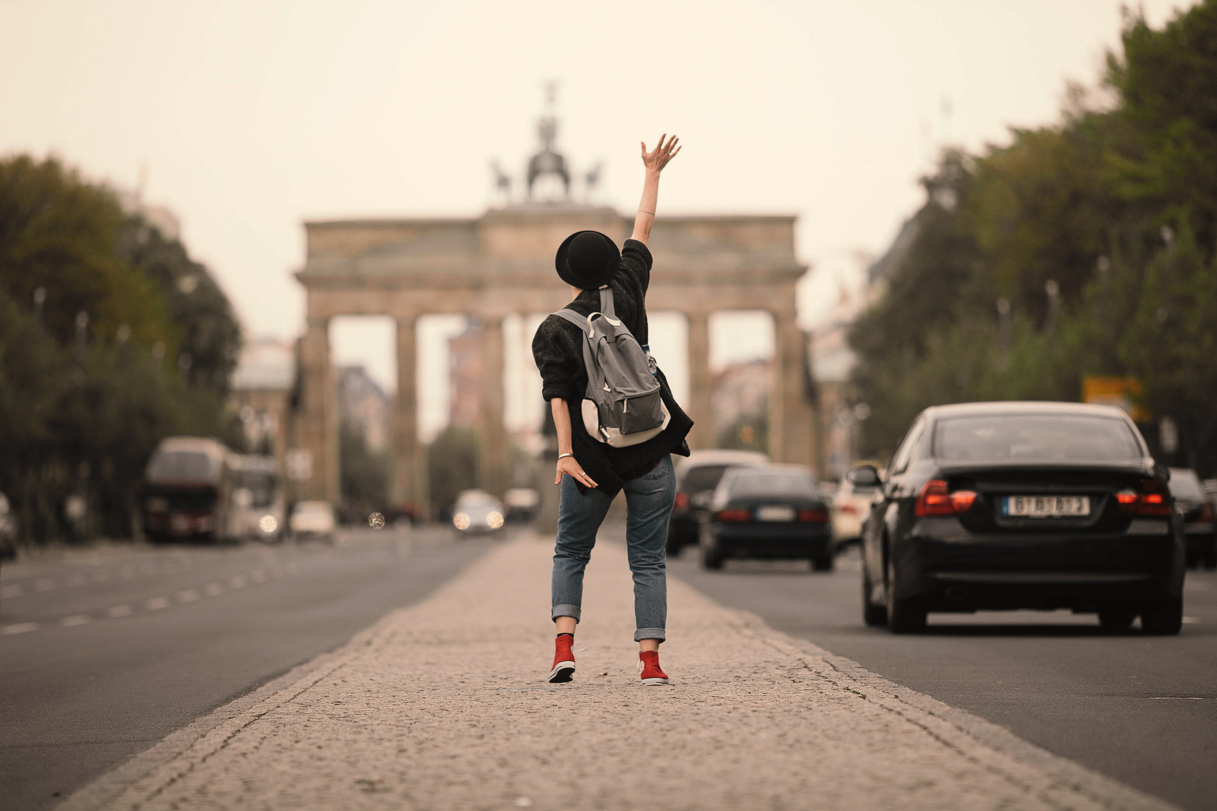 Person with a backpack in front of the Brandenburg Gate in Berlin.