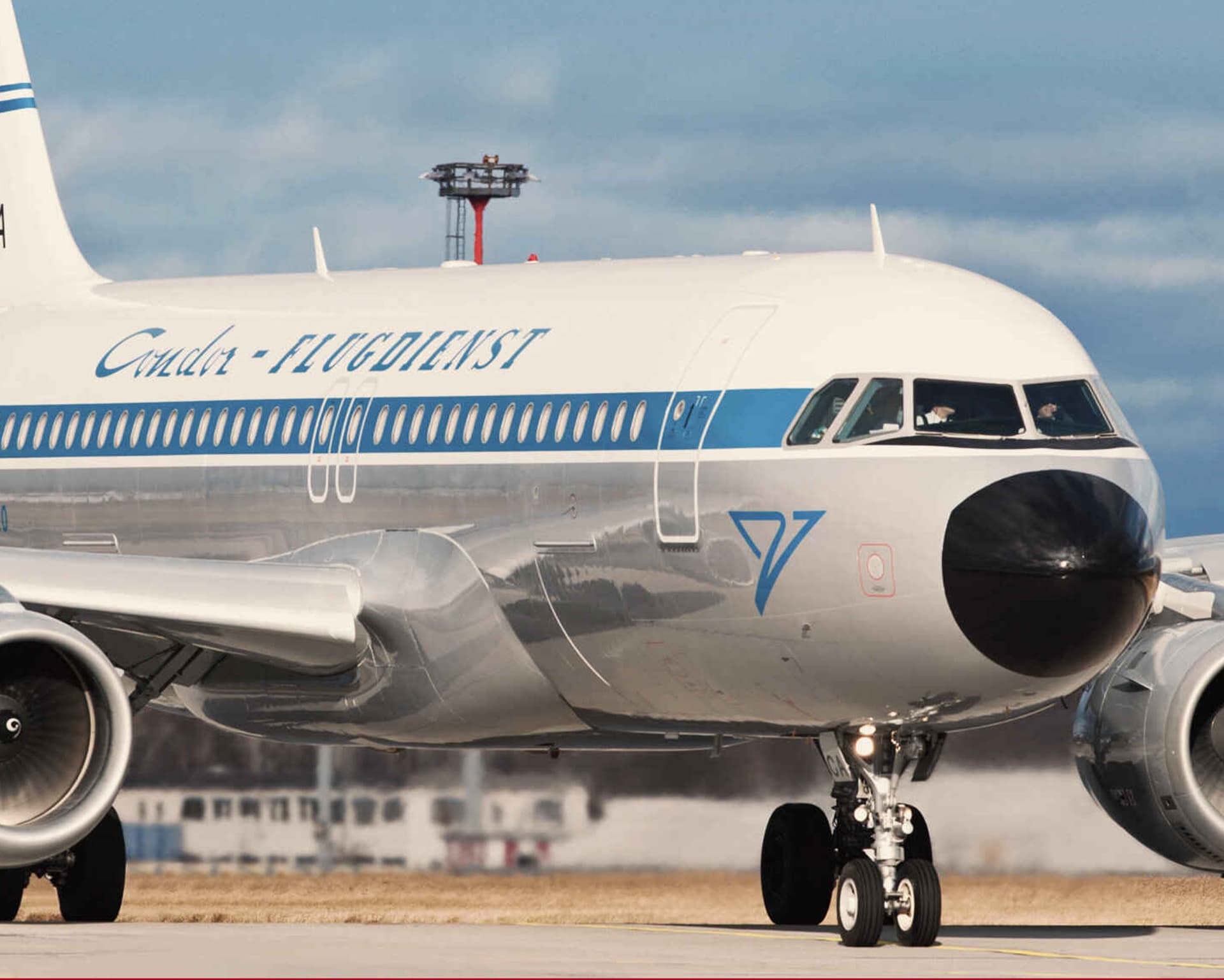 A close-up of the nose of a passenger aircraft in the historic Condor livery on an airport apron.